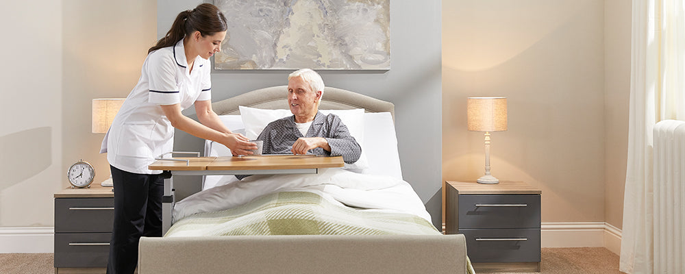 a carer giving an elderly man his food in bed