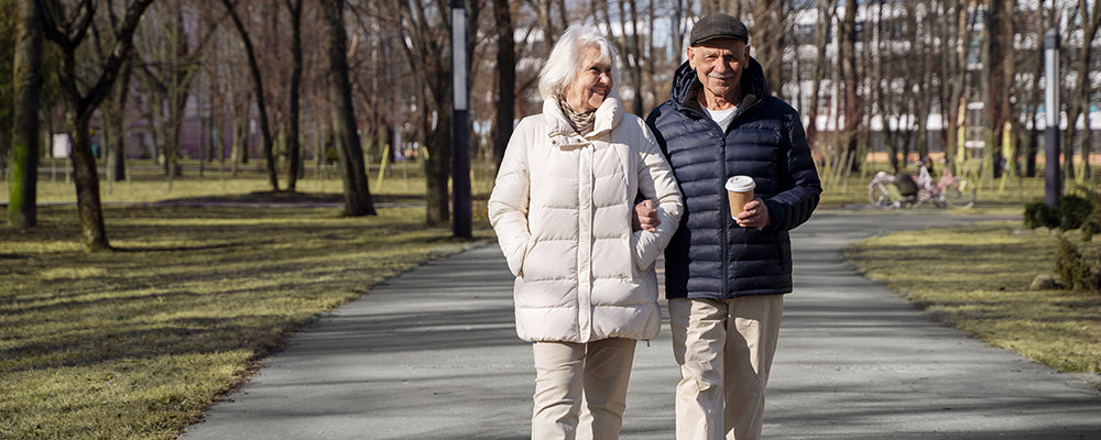 Older couple walking through a park linking arms