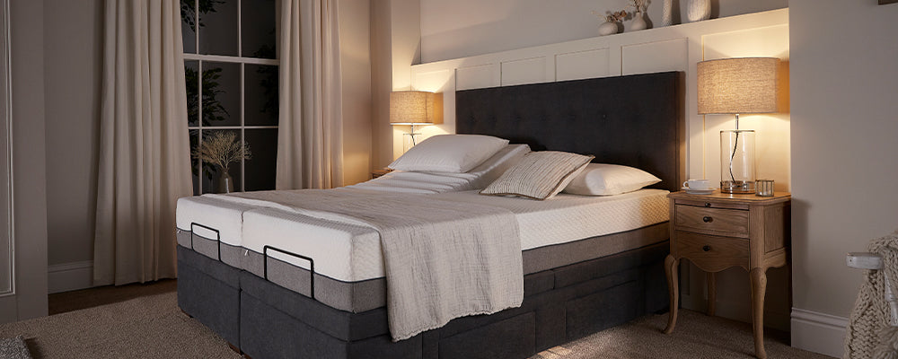 Grey king size bed in bedroom with two bedside lamps on 