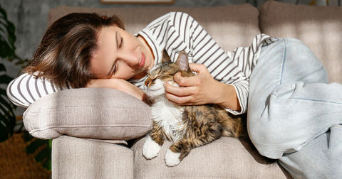 woman laying on couch rubbing cat