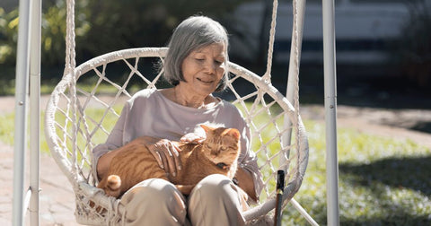 old lady holding cat in garden chair outside