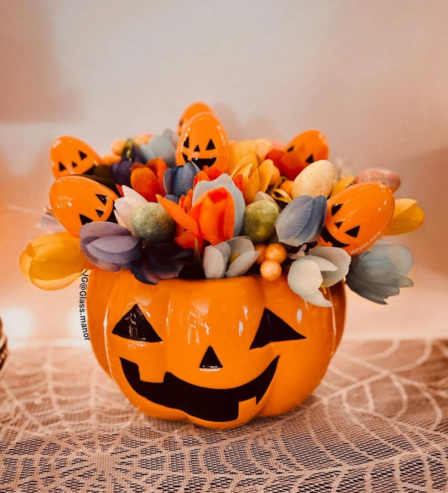A pumpkin jack o lantern bucket filled with flowers and orange easter eggs, perfect for easterween easter-ween halloween easter spooky easter.