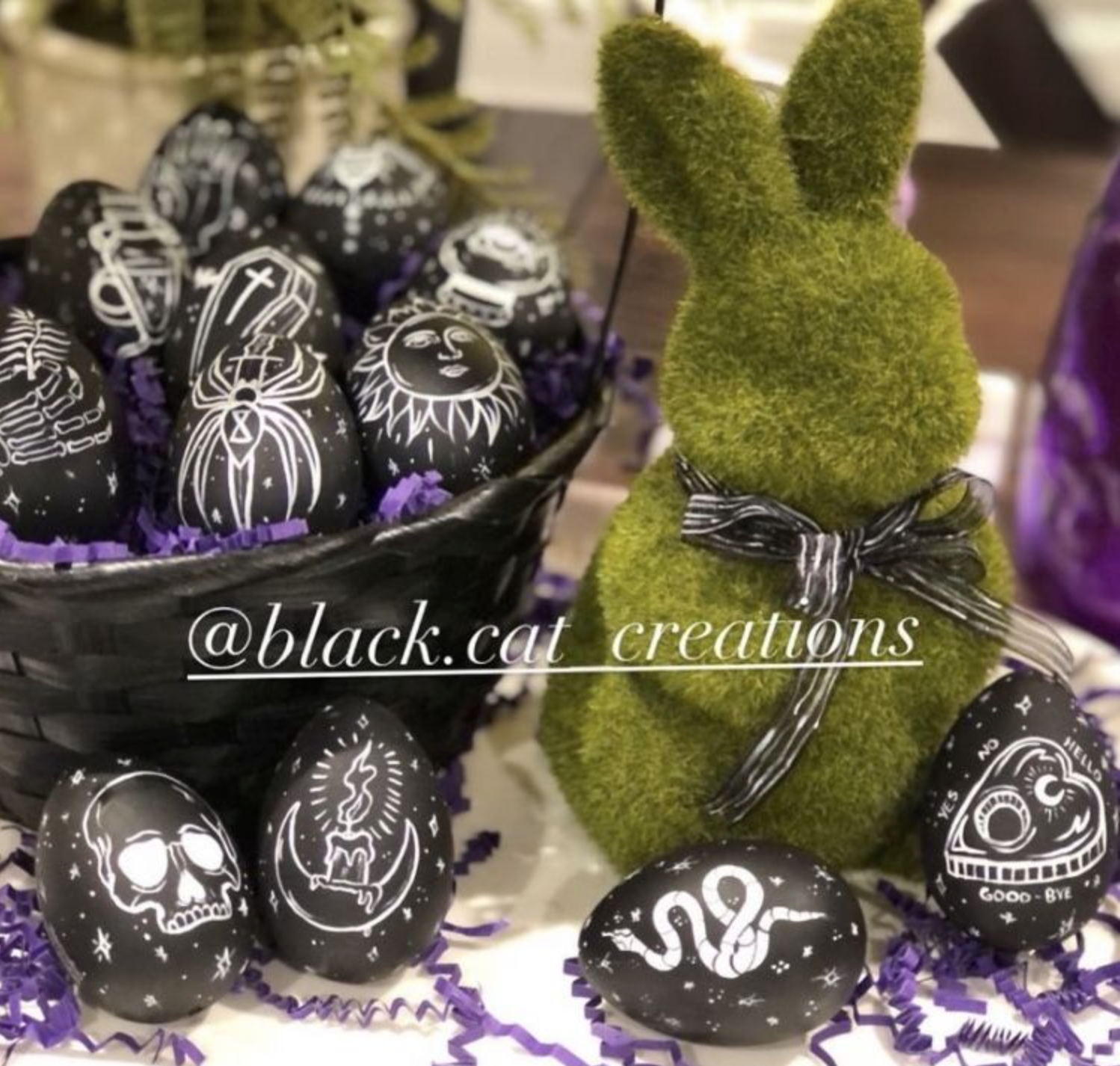 Green faux grass fuzzy easter bunny decoration next to easterween easter-ween easter halloween themed painted black easter eggs in a basket