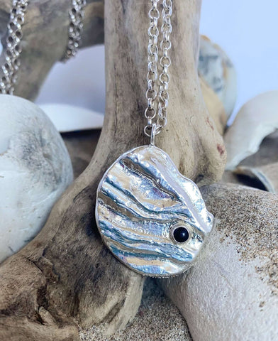 Close up of new 'Ripples" pendant in sterling silver, with bezel set onyx cabochon, from the new "Shoreline" collection