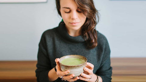 woman looking down at cup of matcha green tea