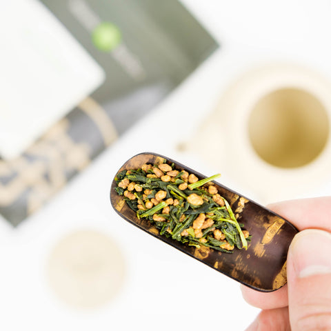 Organic genmaicha loose leaf tea displayed on a cherry wood tea scoop