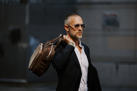 man holding brown briefcase over shoulder