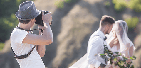 "A professional wedding photographer capturing a candid moment between the bride and groom, expertly framing the image to preserve the couple's special day."