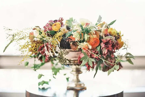 "A beautiful Thanksgiving flower centerpiece with autumn blooms and foliage."