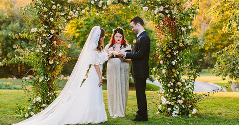"A picturesque outdoor wedding ceremony, with the bride and groom standing beneath a beautiful floral arch, exchanging vows as guests look on with joy."