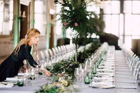 "A wedding planner meticulously arranging floral centerpieces and table settings at the wedding venue, ensuring every detail is perfect for the upcoming celebration."