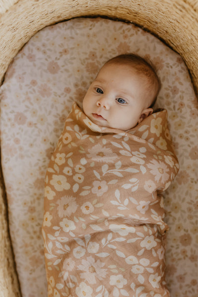 newborn baby girl swaddled in a floral cotton blanket