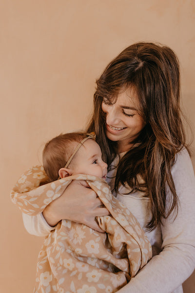 mama holding baby girl wrapped in a floral baby blanket