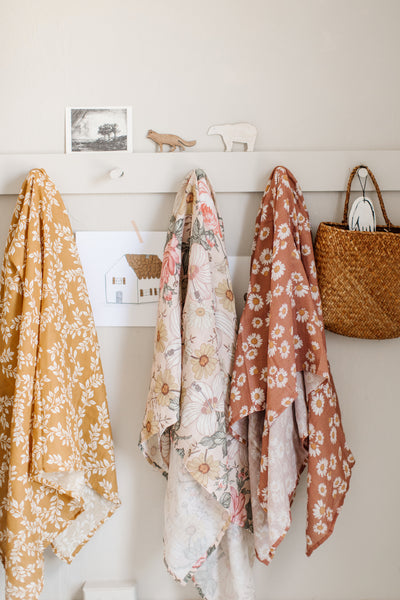 an organized baby room with a cute hanging shelf with pretty muslin receiving blankets on the hooks