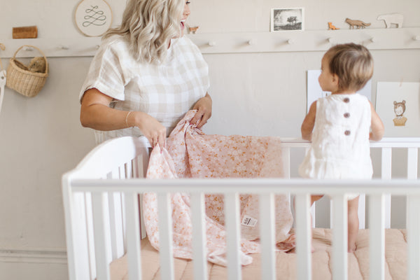 a mama and a baby in a clean nursery, a pretty peachy pink floral blanket