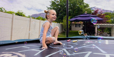 Young girl sits on trampoline with chalk