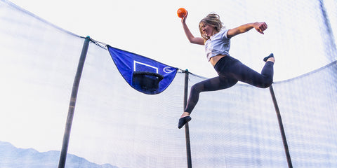 Young girl dunking a basketball into the basketball hoop