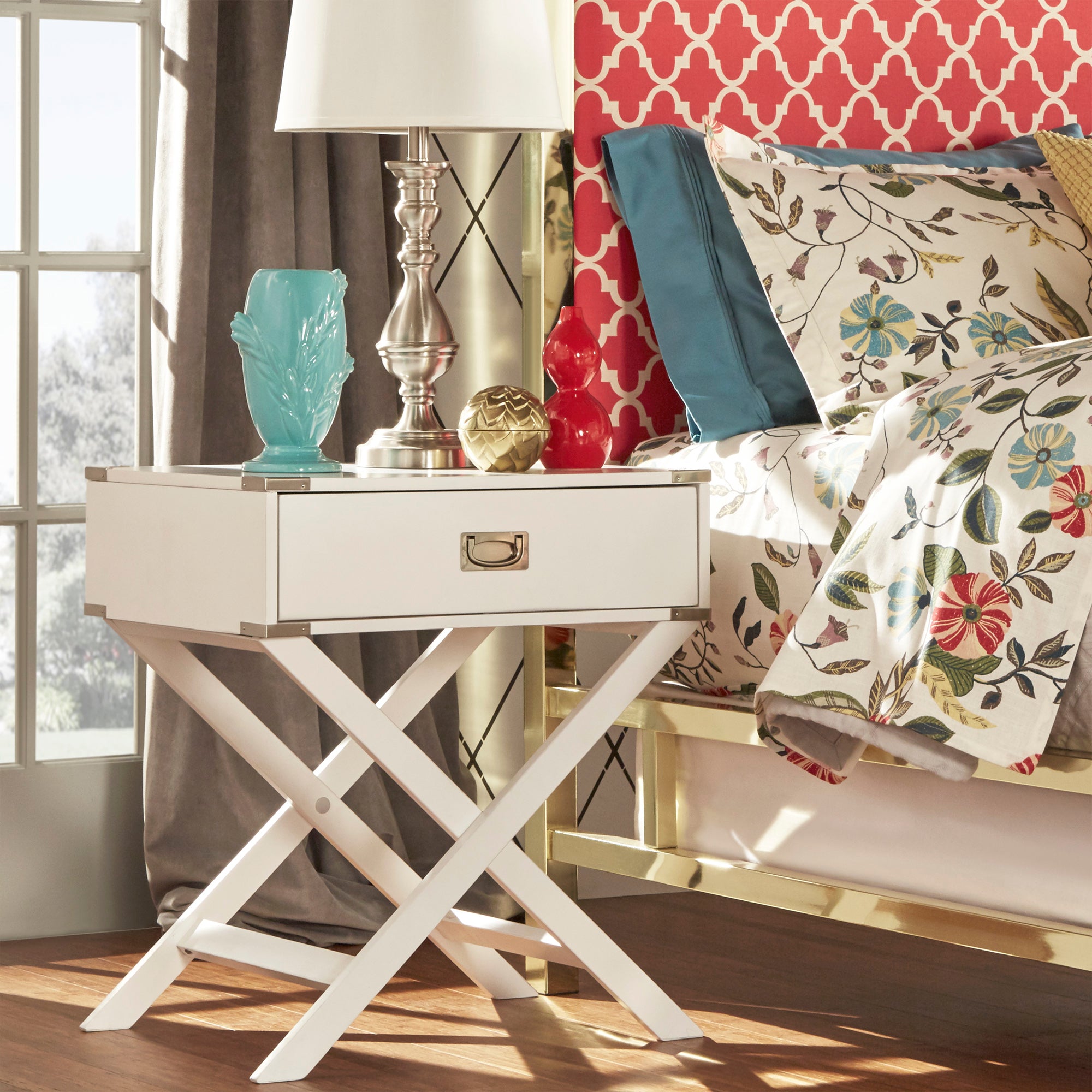 Campaign is one of those furniture terms to know that has a bit of history to it! It has a distinct style that is deeply rooted to its origins as being furniture made for traveling. This image depicts the White X-Base Wood Accent Campaign Table by iNSPIRE Q Bold. The table top is decorated with a lamp and some colorful pieces of décor.