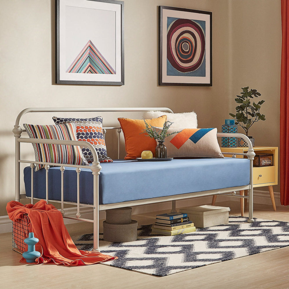 For this one of our spring style ideas for daybeds, our white Victorian metal daybed features a more modern look. The mattress has a crisp blue sheet, while the pillows are blue, white, and orange with various prints. There is also a matching orange throw blanket to the side, and a black and white zigzag printed rug.