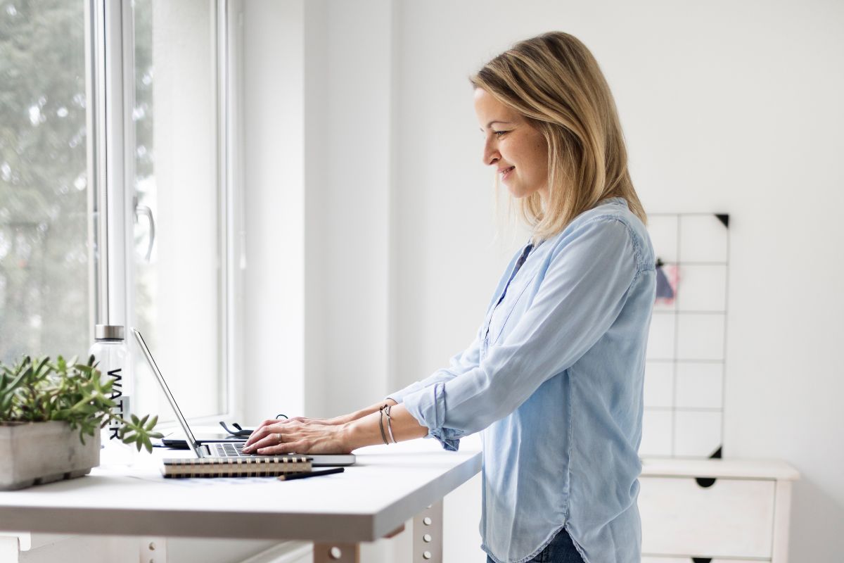 Woman using standing desk with a smile on her face.
