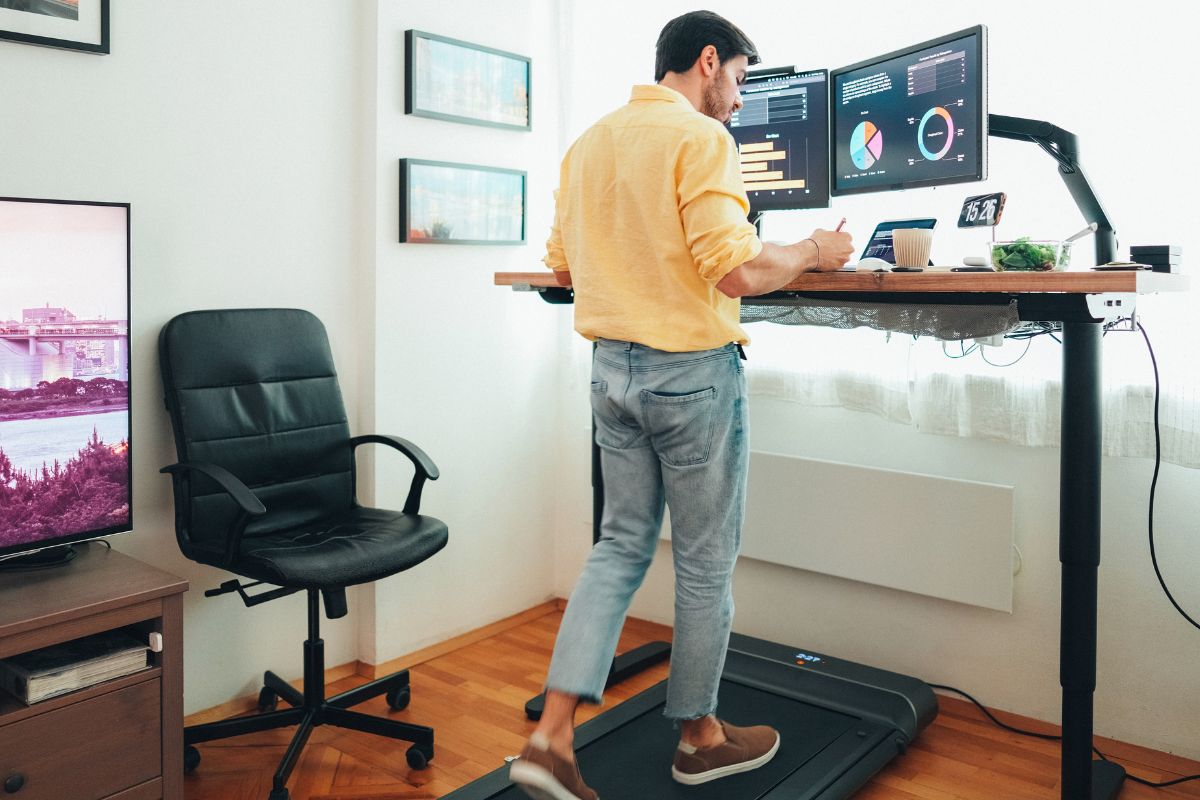 Man using treadmill while working at a standing desk.