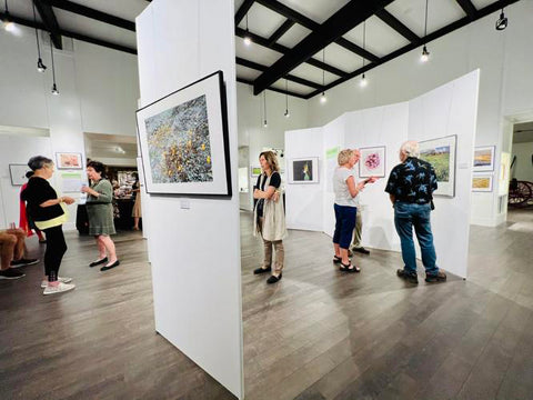 Patrons study the colorful photographs of California’s wildflowers during Sutter County Museum’s opening reception of “Beauty and the Beast: California Wildflowers and Climate Change”