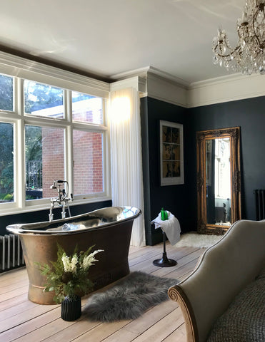 pale floorboards in a dark bedroom with a bath in the bay window