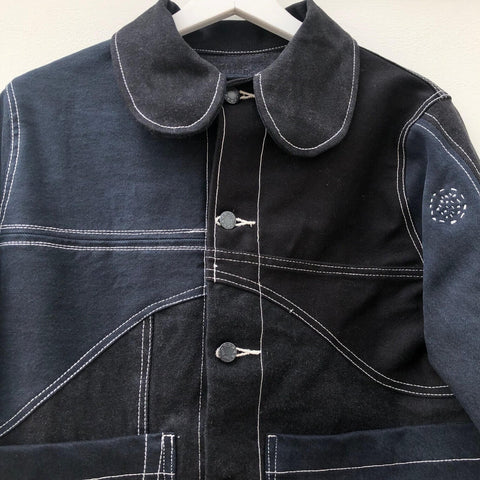 Black denim jacket with curved seam detailing and a contrasting white top stitch