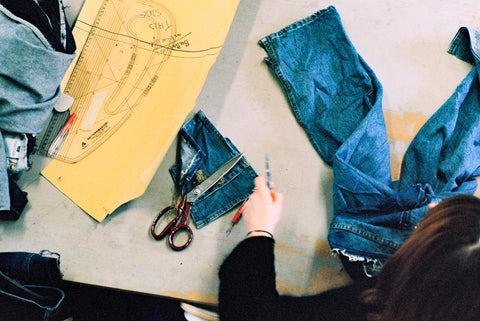 a cutting table with patterns, denim and shears.