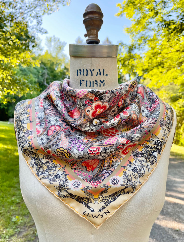 This Italian silk bandana is rich with sunset colored wildflowers and energized leopards romping around the border tied around the neck of a dress form. 