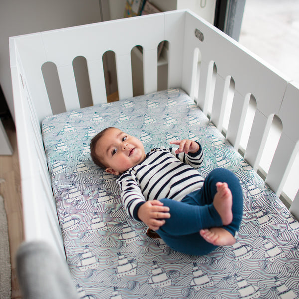 baby in white alma papa crib