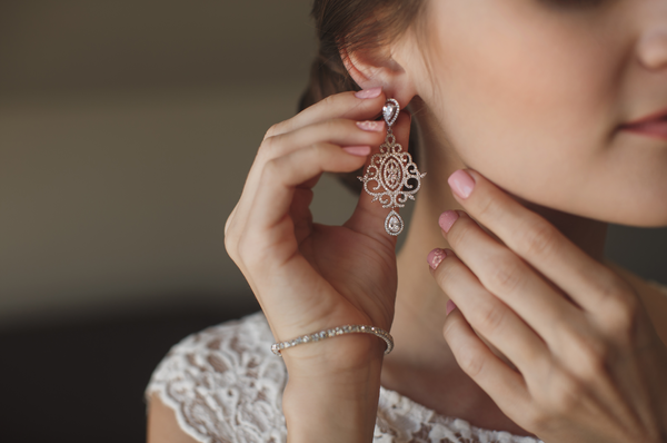 Mujer colocando aretes o pendientes en sus orejas para lucir más bella y complementar su look