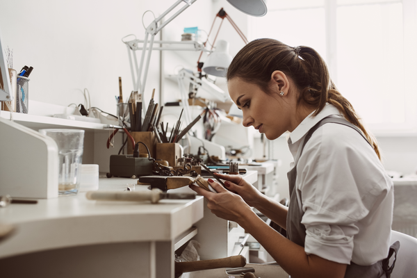 Mujer joyera limpiando y puliendo una joya con todo su equipo y herramientas de trabajo