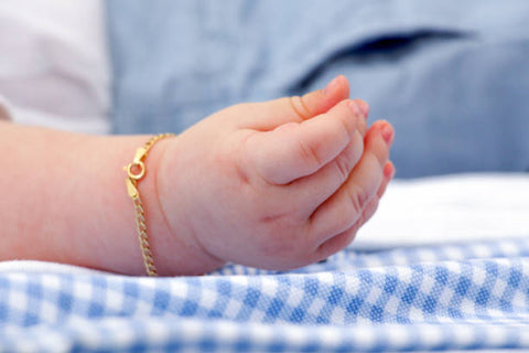 mano de bebé con pulsera de oro