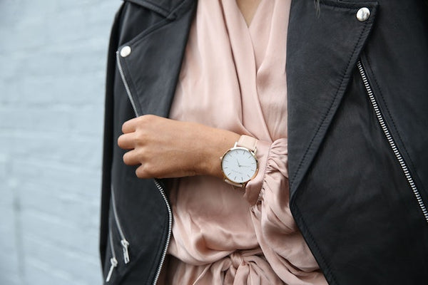 Mujer con reloj en brazo y mostrándolo al agarrar con la otra mano su chaqueta