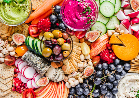 Image of a charcuterie board with crackers, vegetables, and other snacks