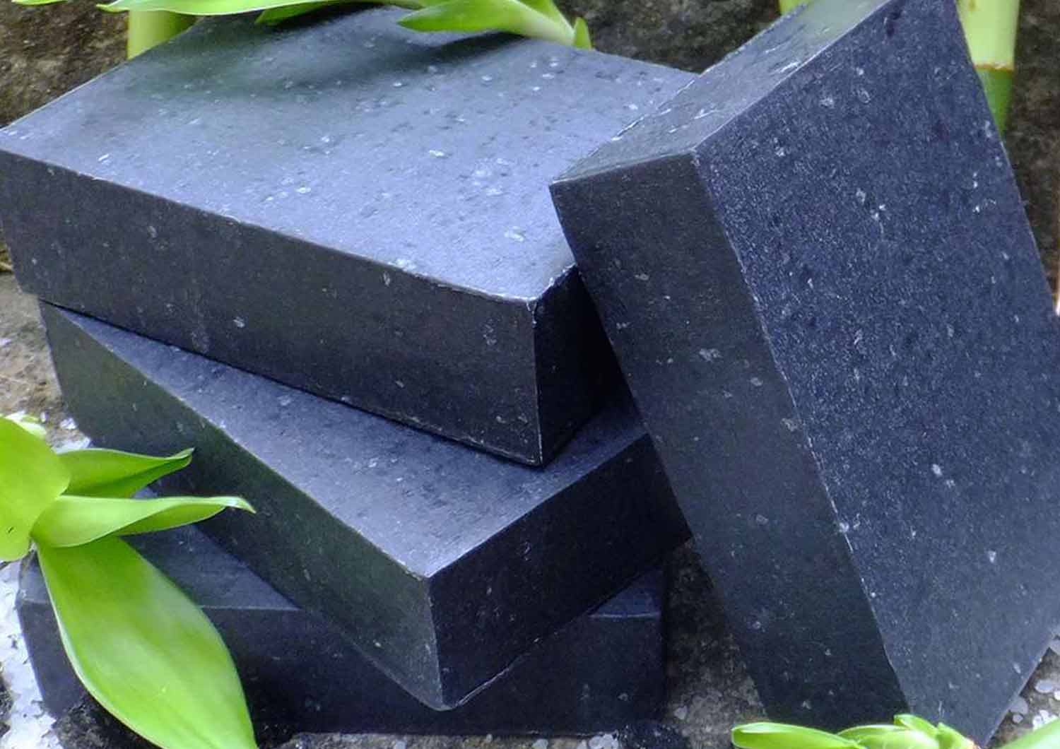 bars of charcoal soap on rocks and leaves in forest