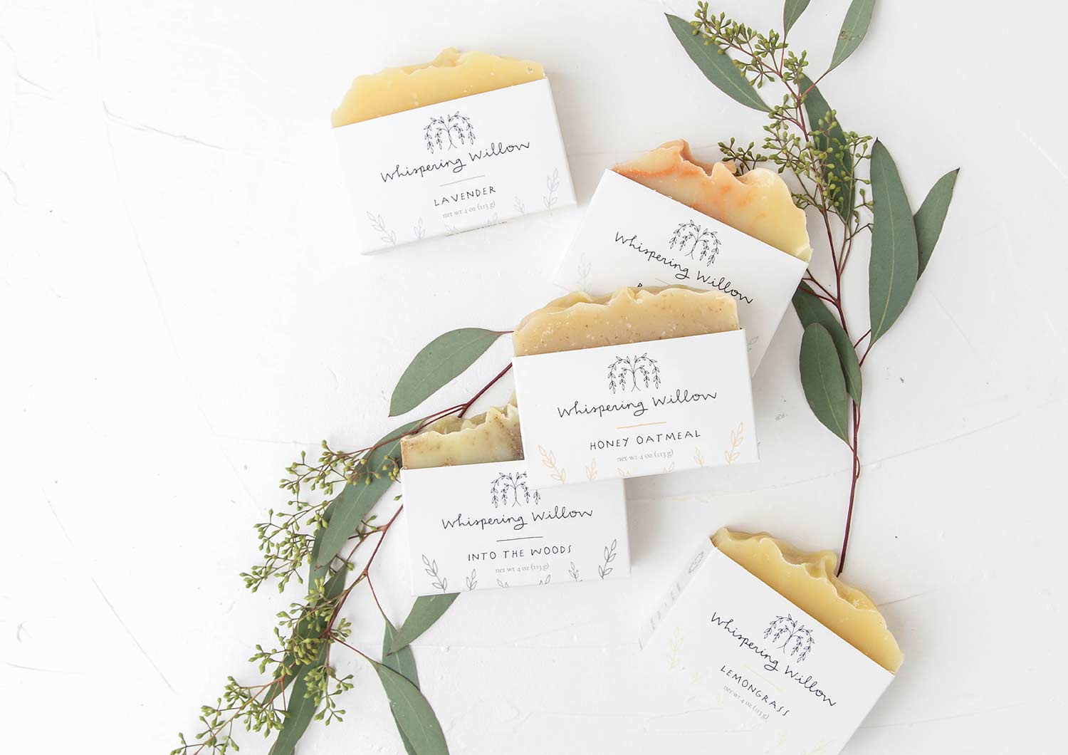 bars of whispering willow sustainable soap laying on leaves and twigs white background