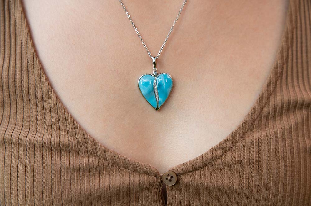 ocean blue larimar heart pendant lined with white topaz in the middle worn by a model