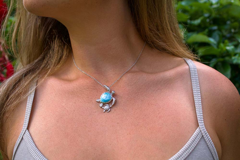 a mom wearing a sterling silver sustainable ocean blue opal sea turtle featuring a mother and child sea turtle design