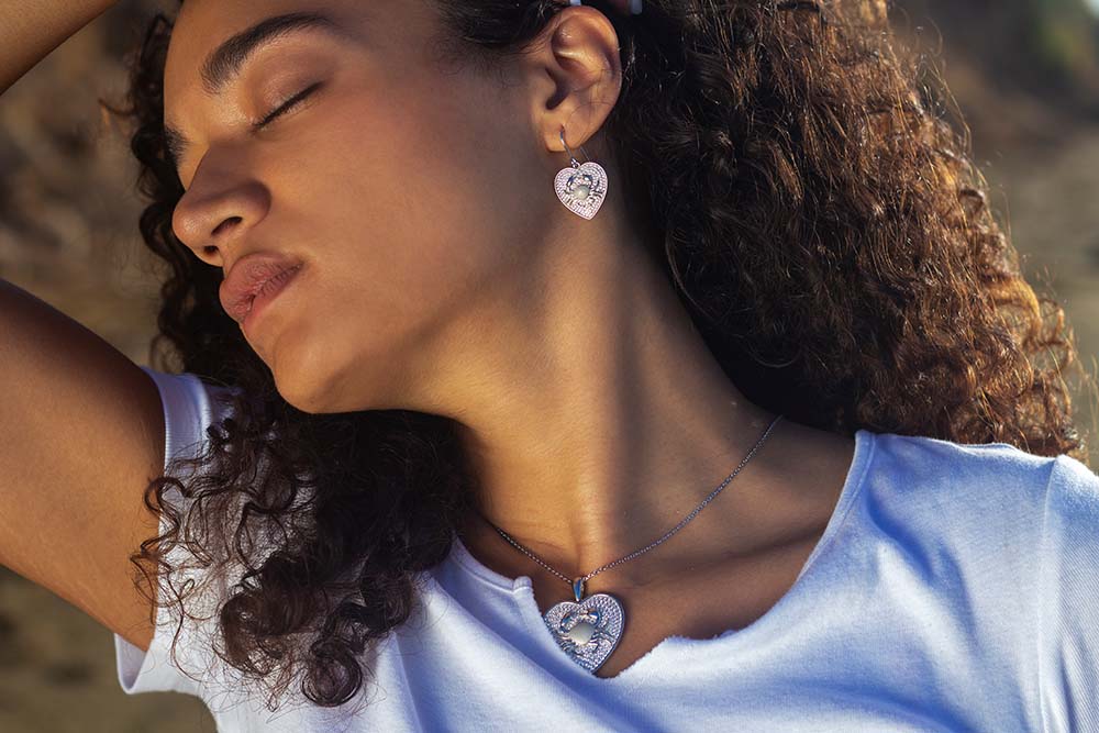 Yoga instructor rae wearing pavé crab heart jewelry set with earrings and pendant, lined with white topaz