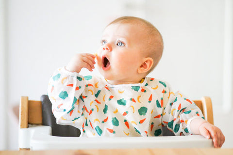 Baby sitting in high chair ready to put hand in mouth