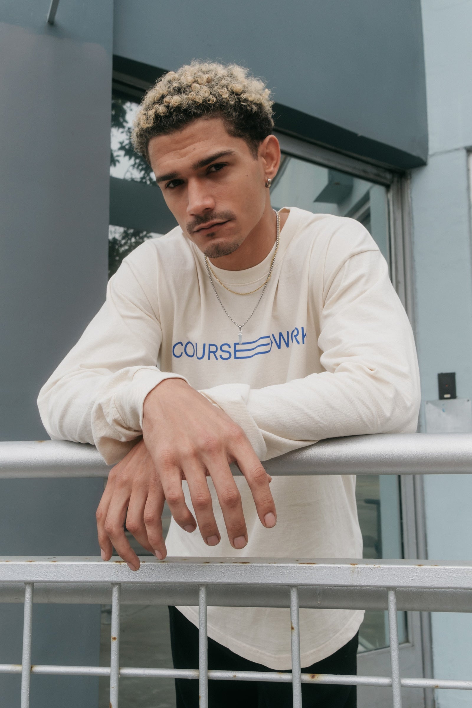 Model wearing the Full Width Text Long Sleeve Tee and leaning on a handrail.