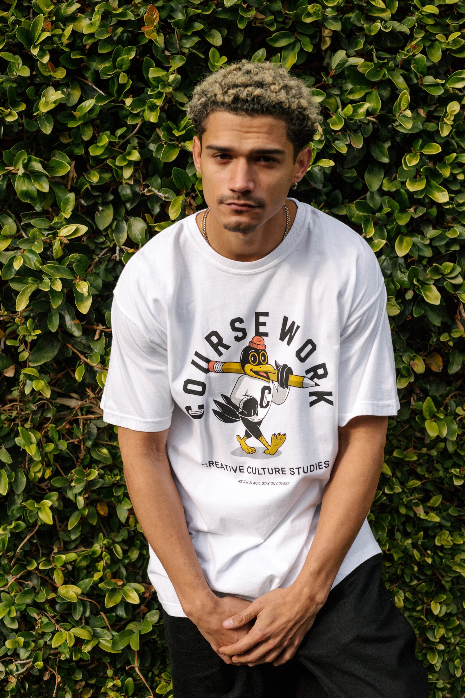 Model wearing the Early Birds tee with green foliage behind him.