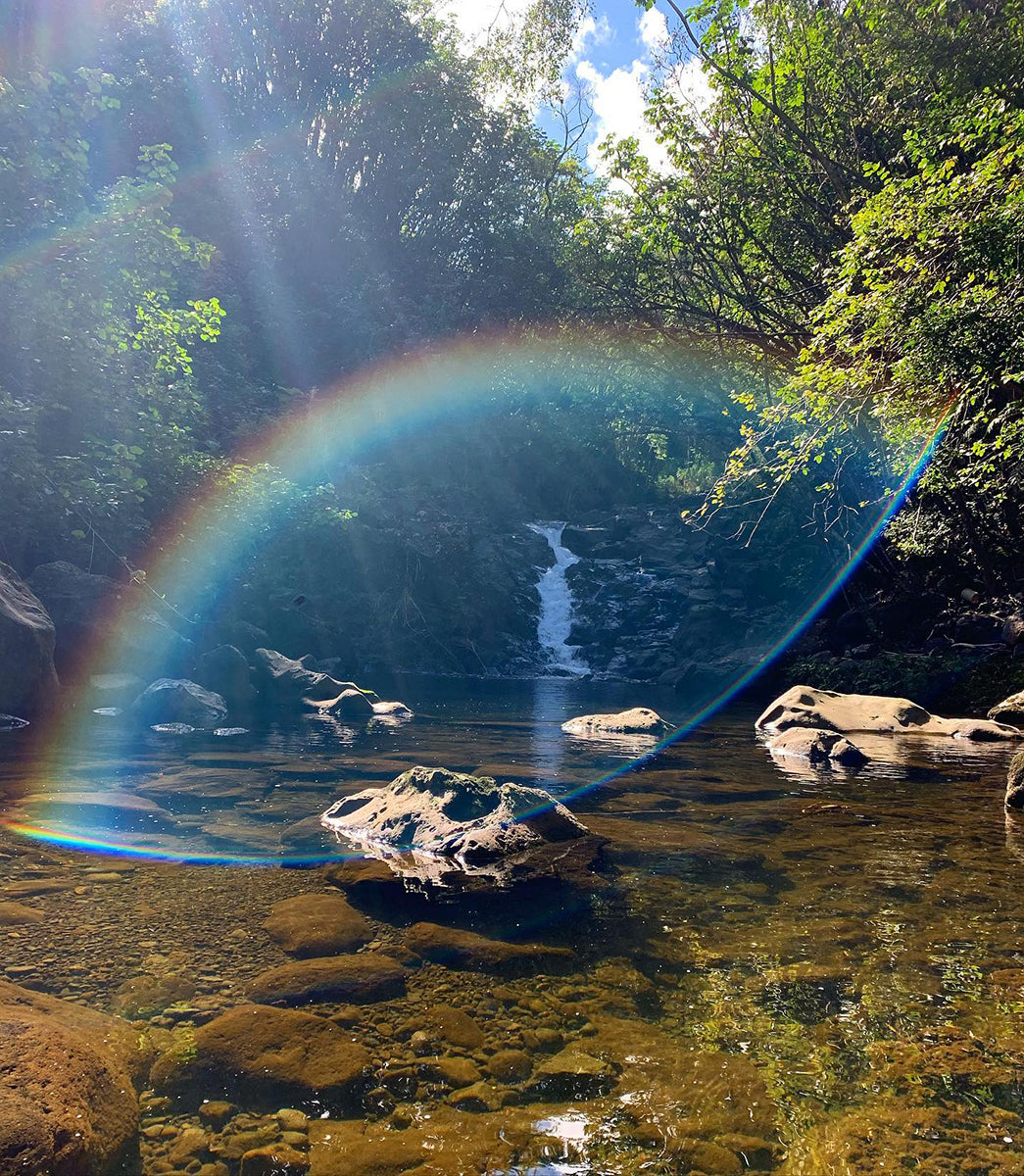 A ray of light hits the camera lens to create a rainbow over the waterfall.