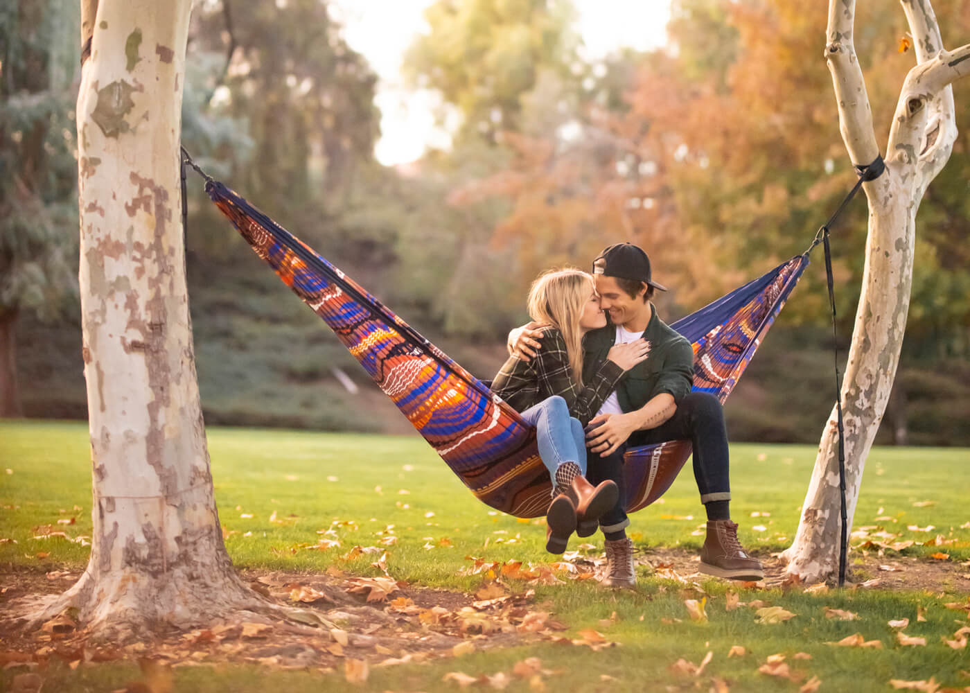 A couple snuggles up while sitting in a Tundra DoubleNest Hammock Print during autumn.
