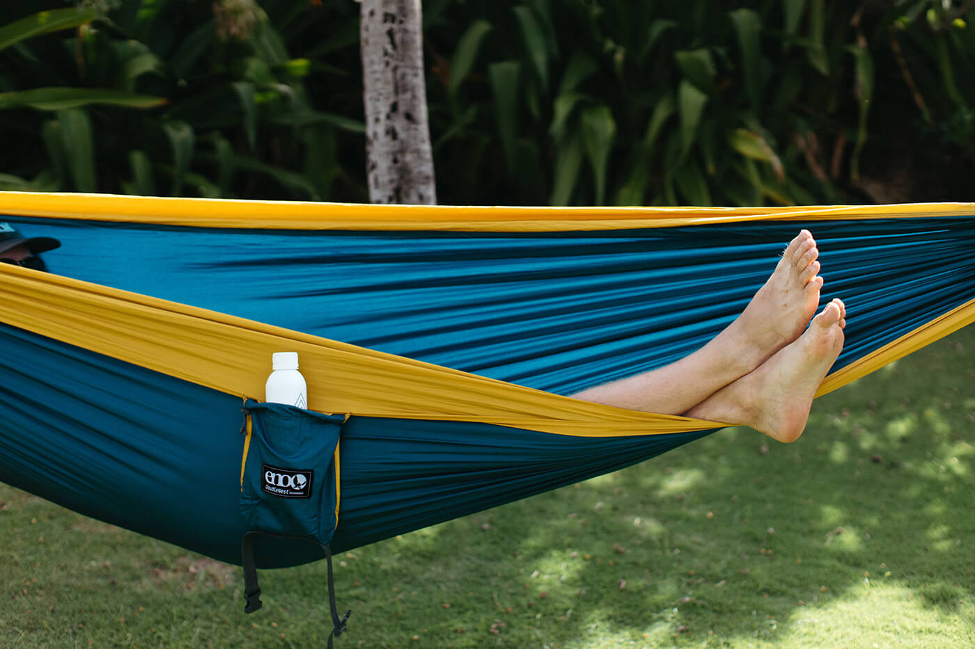 A man lays in a Marine Gold DoubleNest Hammock with just his feet sticking out.