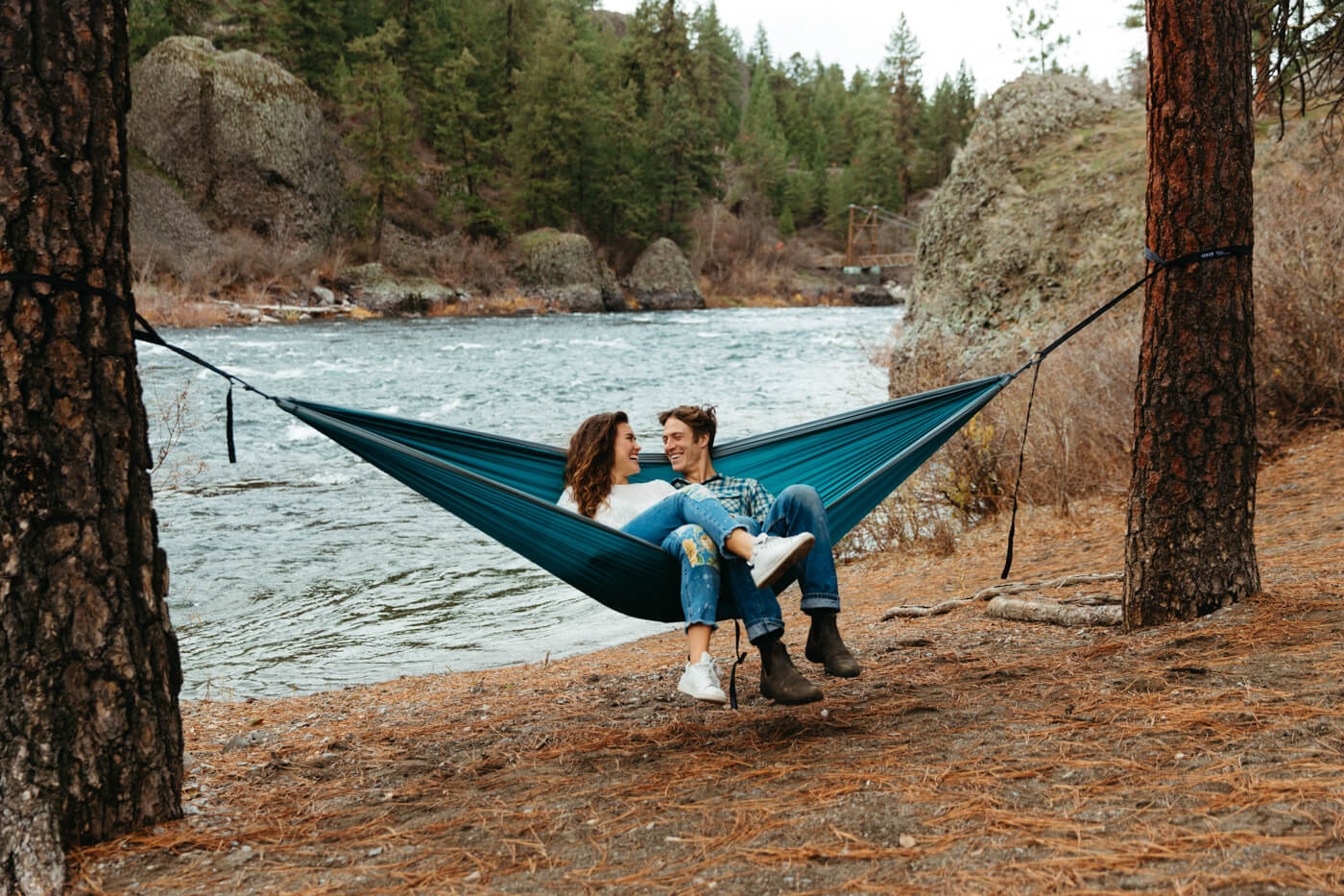 A couple shares an ENO DoubleNest Hammock near a river