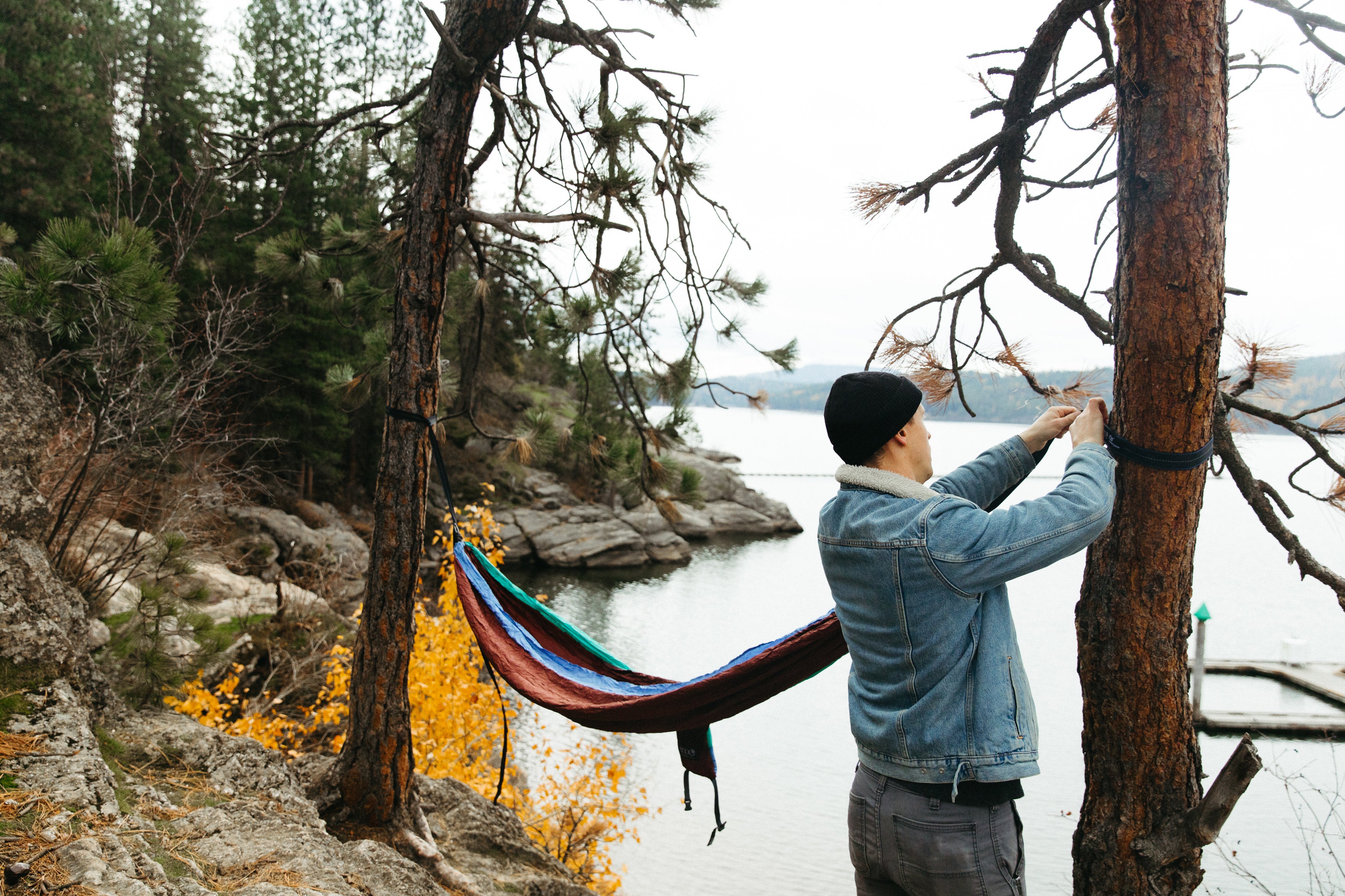 Man hanging an ENO Hammock up by a river.