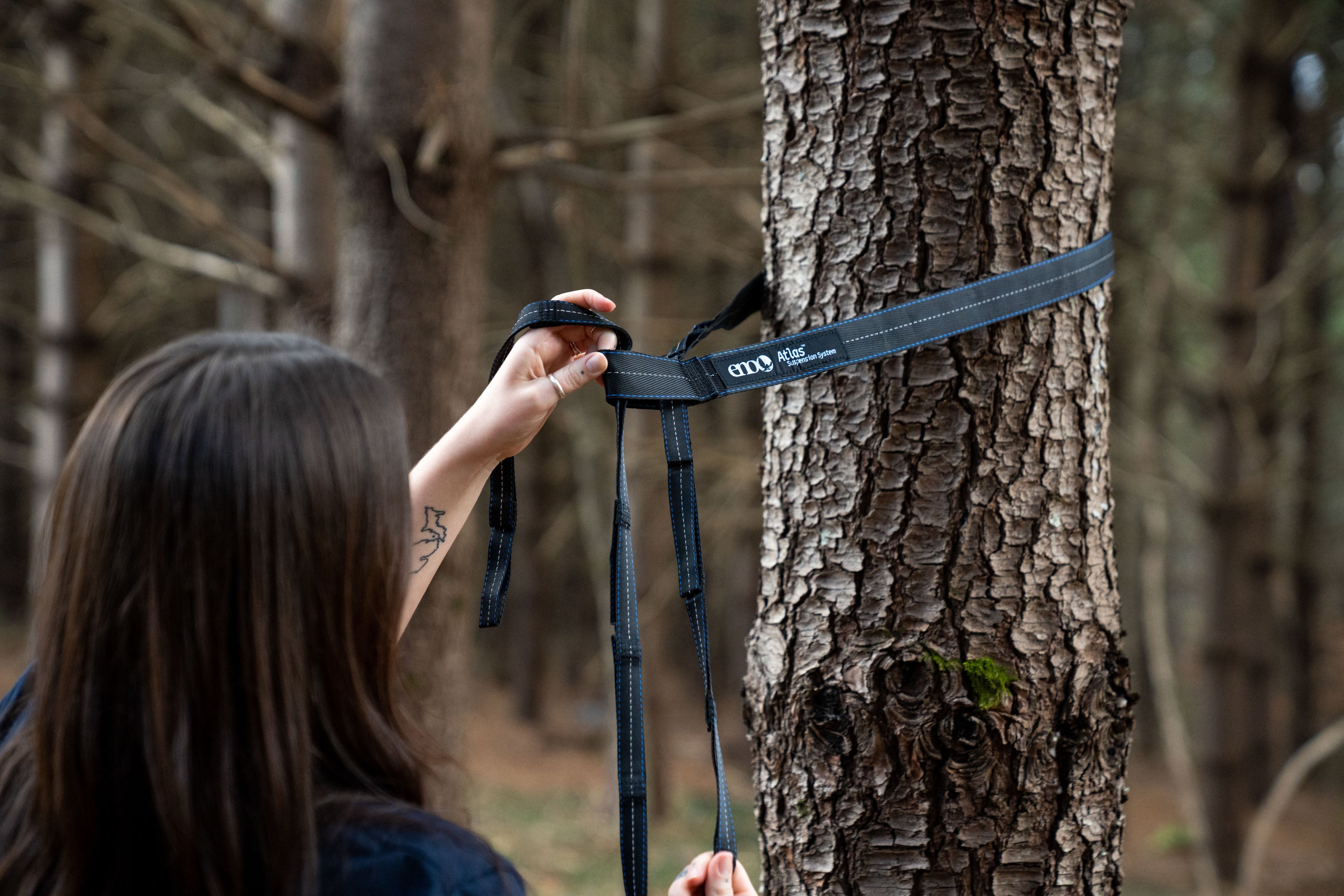 A woman attaching her ENO Atlas Hammock straps to a tree.
